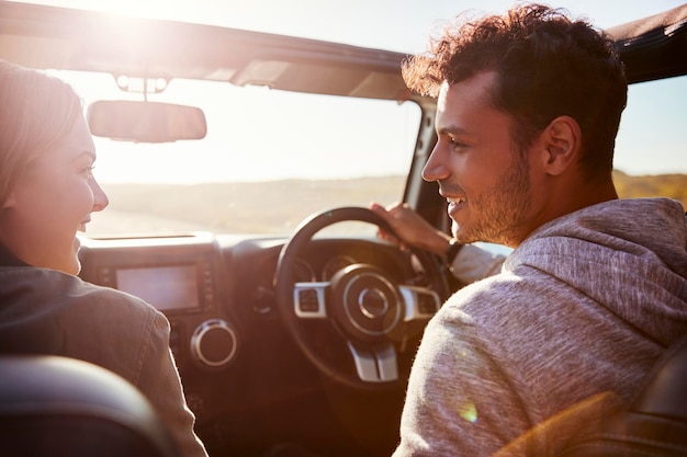 Happy couple driving in car with sunroof open passenger POV