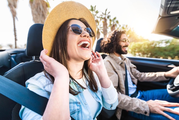 Happy couple driving convertible car enjoying summer vacation