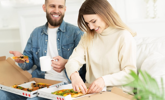 Happy Couple Eating Pizza Relaxing On Weekend At Home