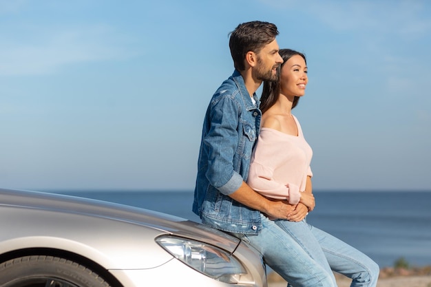 Happy couple embracing each other leaning cabriolet