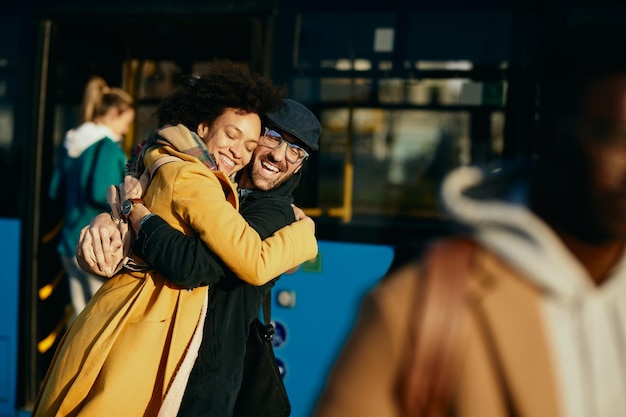 Happy couple embracing with eyes closed while meeting at bus station