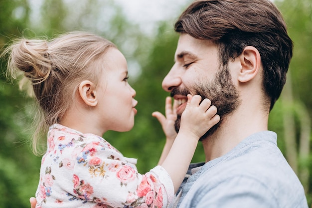 Happy couple of father and his young daughter having fun in the park on a walk together