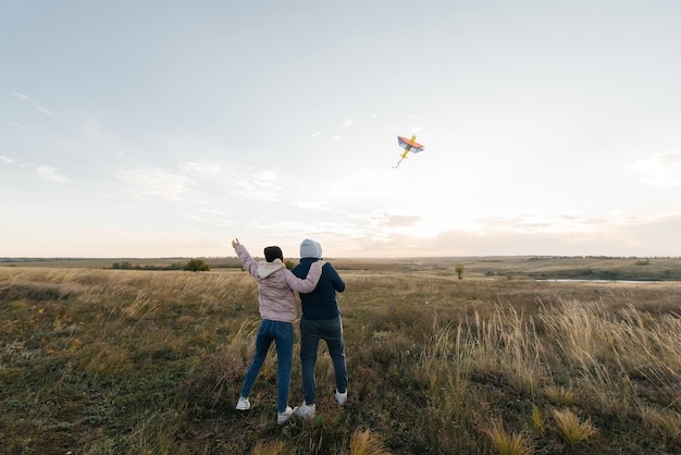 A happy couple flies a kite and spends time together outdoors in a nature reserve Happy relationships and family vacations Freedom and space