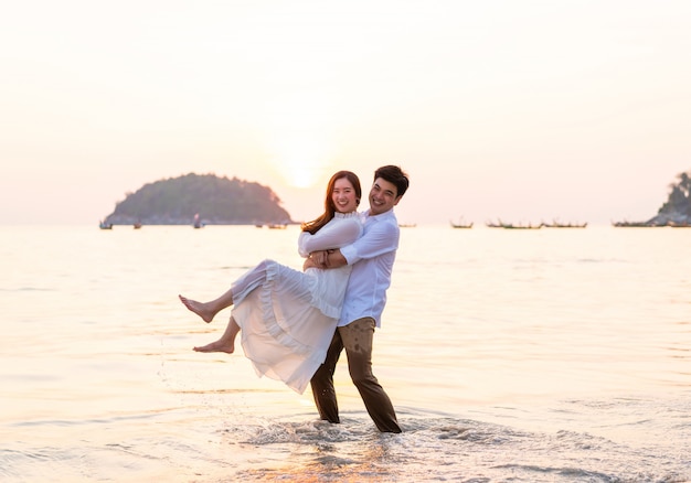 Happy couple going honeymoon travel on tropical sand beach in summer