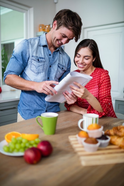 Happy couple having breakfast and reading newspaper at home