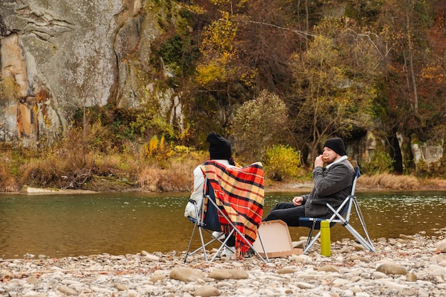 happy couple having picnic at river beach autumn season