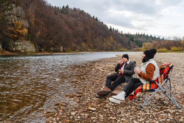 happy couple having picnic at river beach autumn season