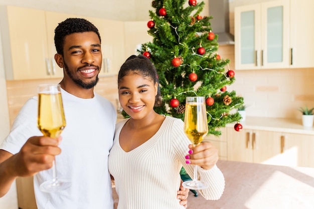 Happy couple holding a glasses of champagne and celebrating new year at home