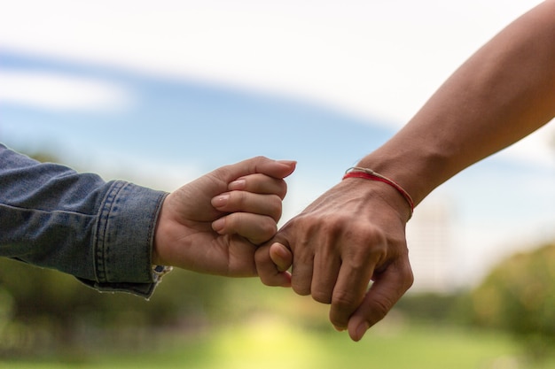 Happy couple holding hands in park with blue sky background. Love concept