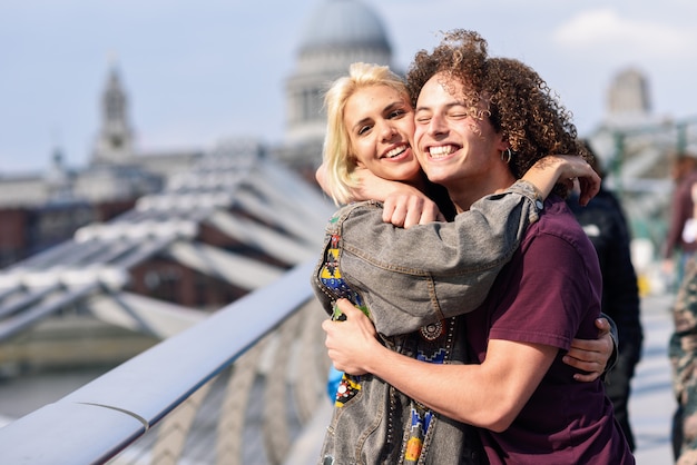 Happy couple hugging by Millennium bridge, River Thames, London.