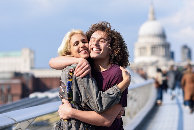 Happy couple hugging by Millennium bridge, River Thames, London.