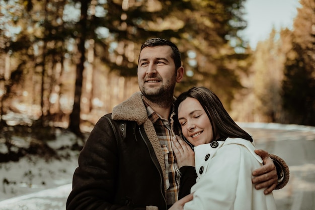 Happy couple hugginng and smiling outdoors in snowy park Selective focus