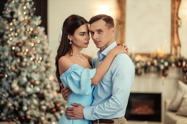 Happy couple husband and wife at home in living room near christmas tree