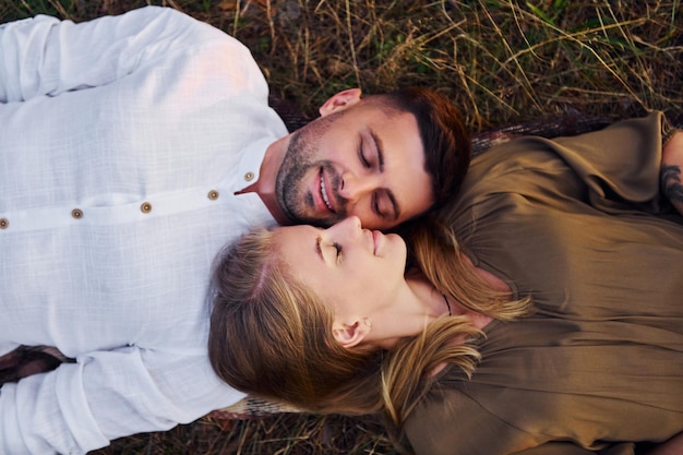 Happy couple is outdoors laying down on the ground