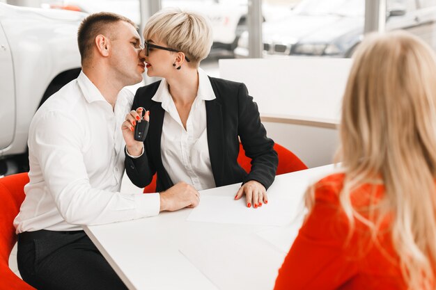 Happy couple kissing holding a car key  in a office after deal