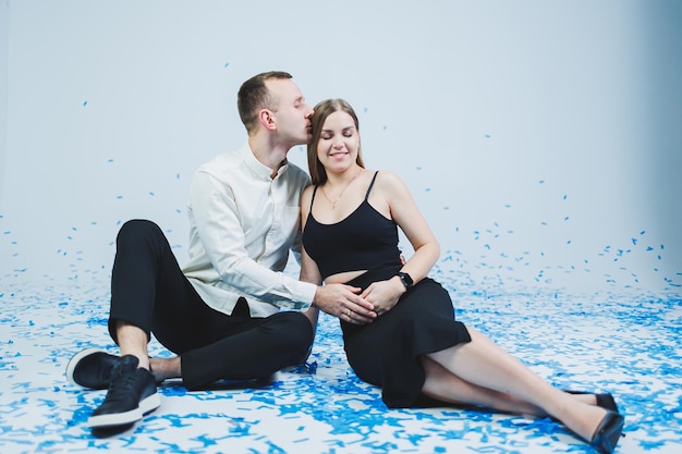 Happy couple laughing at gender party while sitting in blue confetti Gender party