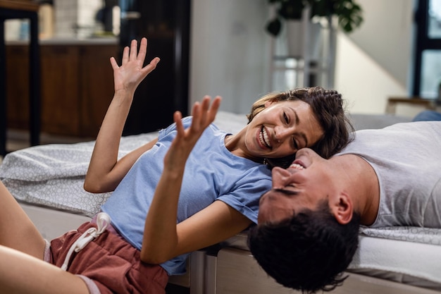 Happy couple laughing together while woman is talking about something funny in the bedroom