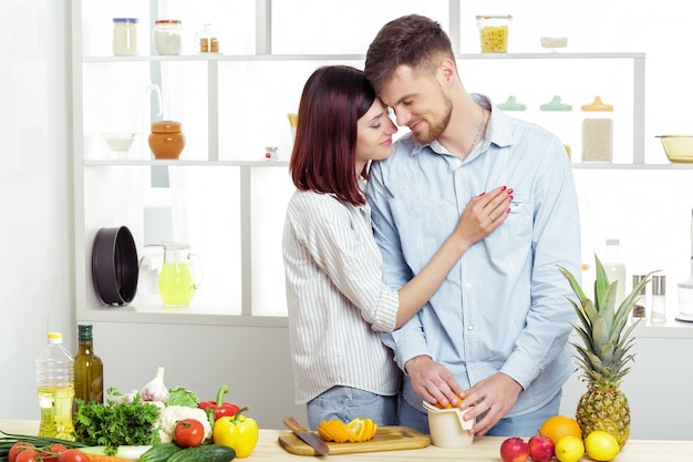 Happy couple in love in the kitchen making a healthy juice from fresh orange