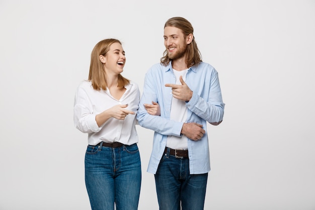 Happy couple love smiling embracing point finger to empty copy space