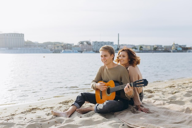 Happy couple in love Stunning sensual portrait of a young couple Young man playing guitar for his beloved girl