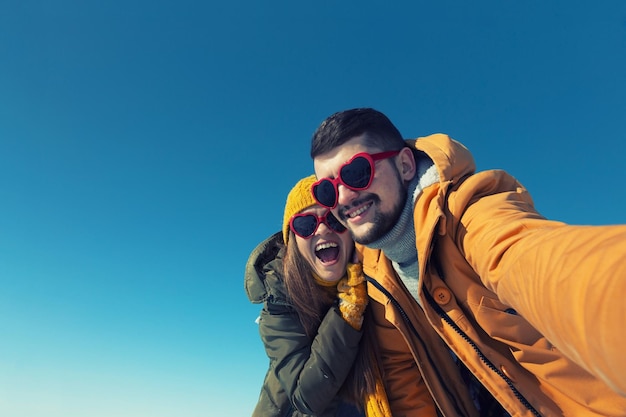 Happy couple making selfie on a winter sunny day Wide angle copy space toned