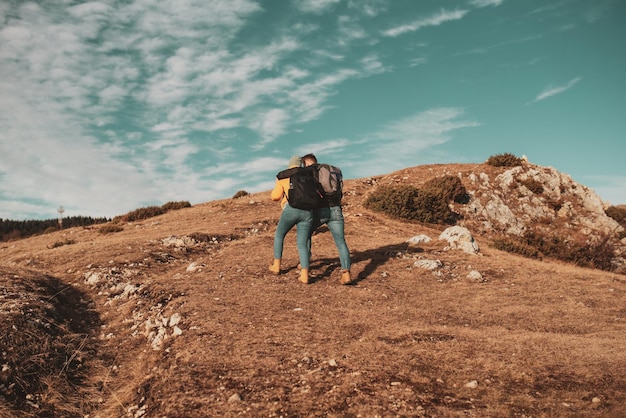 happy couple man and woman tourist at top of mountain during a hike in summer