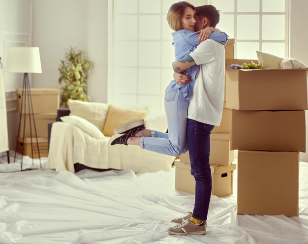 Happy couple moving house boxes around holding keys