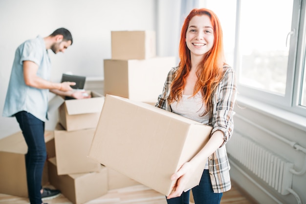 Happy couple moving to new house. Man and woman unpacking cardboard boxes, housewarming