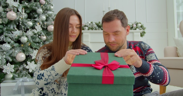 Happy couple opening magical present boxes near Christmas