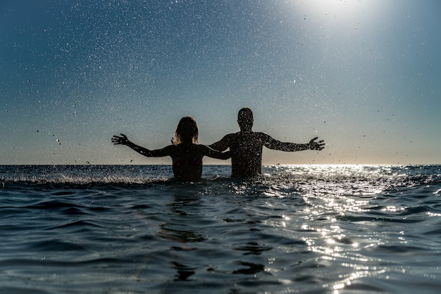 Happy couple playing in the sea. Man and woman having fun on summer vacation. Healthy active lifestyle concept