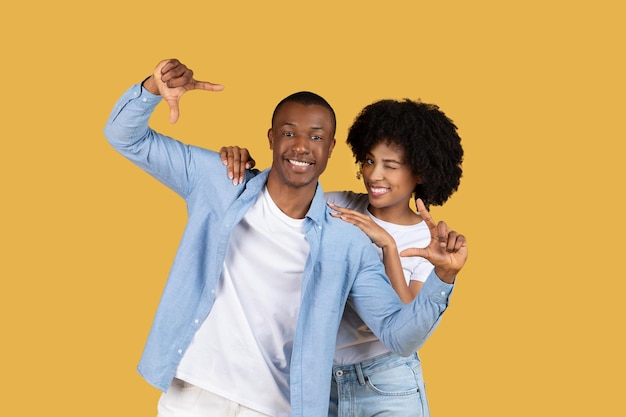 Happy couple posing with thumb gestures on yellow