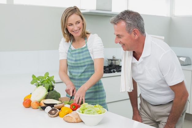 Happy couple preparing food together in kitchen