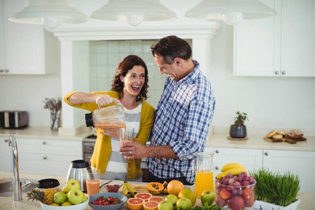 Happy couple preparing smoothie in kitchen