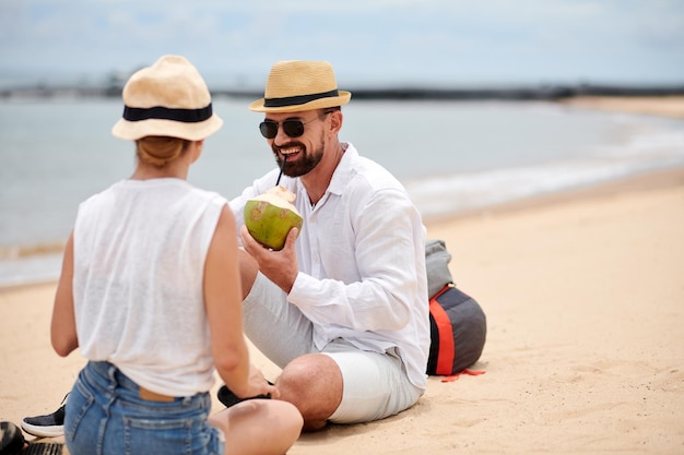 Happy couple relaxing on the beach with coconuts