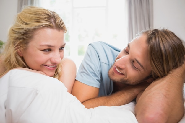 Happy couple relaxing on bed smiling at each other