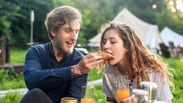 A happy couple resting in the nature at glamping. Drinks and food, greenery around