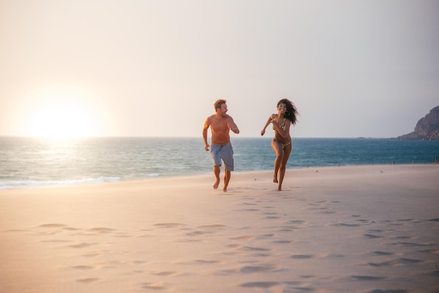 Happy couple running on tropical romantic beach