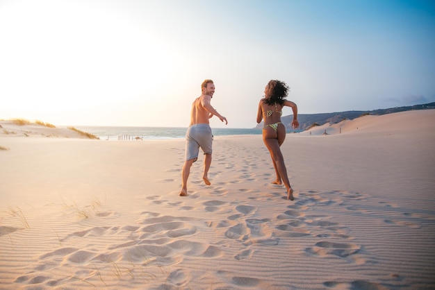 Happy couple running on tropical romantic beach