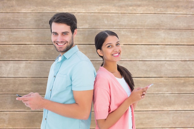 Happy couple sending text messages against wooden surface with planks