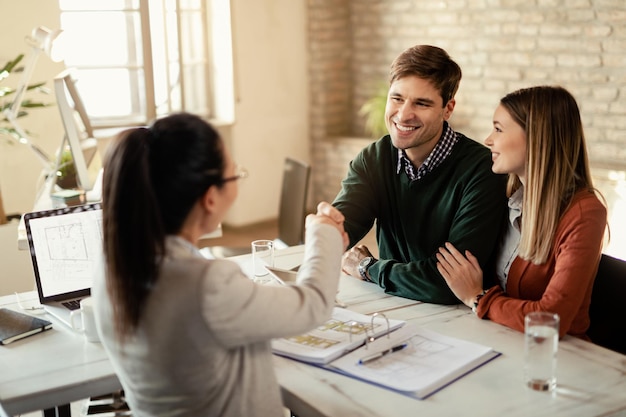 Photo happy couple shaking hands with insurance agent on a meeting in the office focus is on man