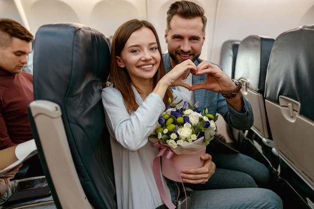 Happy couple showing heart symbol in airplane