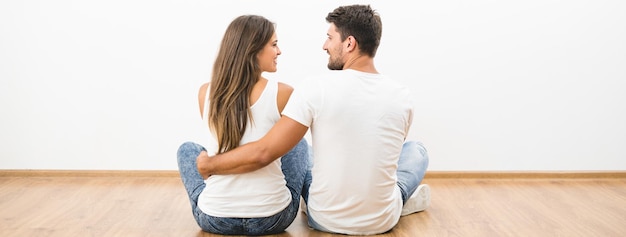 The happy couple sit on the background of the white wall