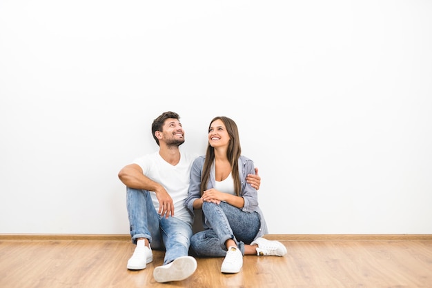 The happy couple sit on the background of the white wall