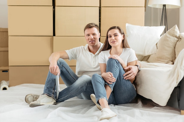 Happy couple sitting near boxes in a new apartment.