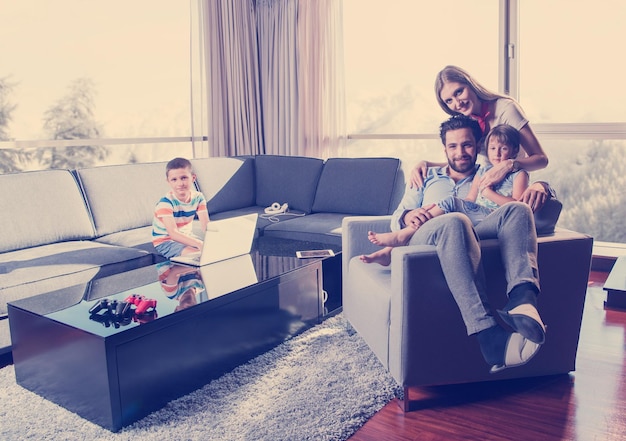 happy couple spending time with kids using tablet computer on an armchair  at home