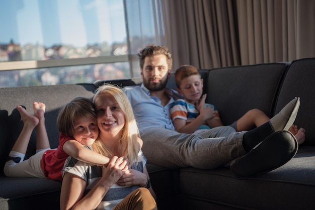 happy couple spending time with kids using tablet computer on sofa at home