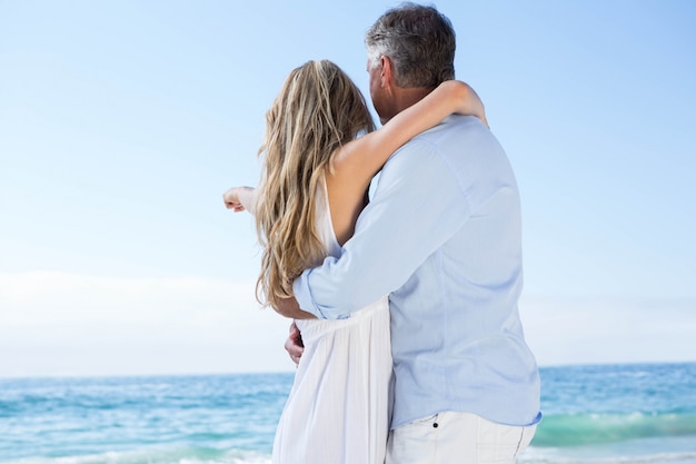 Happy couple standing by the sea and pointing something 