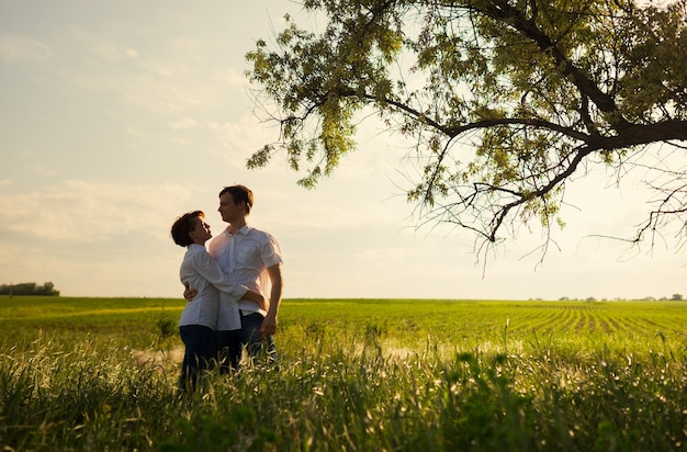 Happy couple standing in the field at the sunset