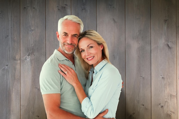 Photo happy couple standing and smiling at camera against wooden planks