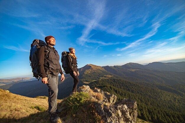 The happy couple standing on the sunny mountain